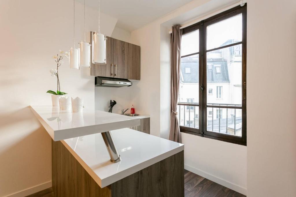 a kitchen with a white counter and a window at Charmant studio neuf proche Tour Eiffel (G36) in Paris