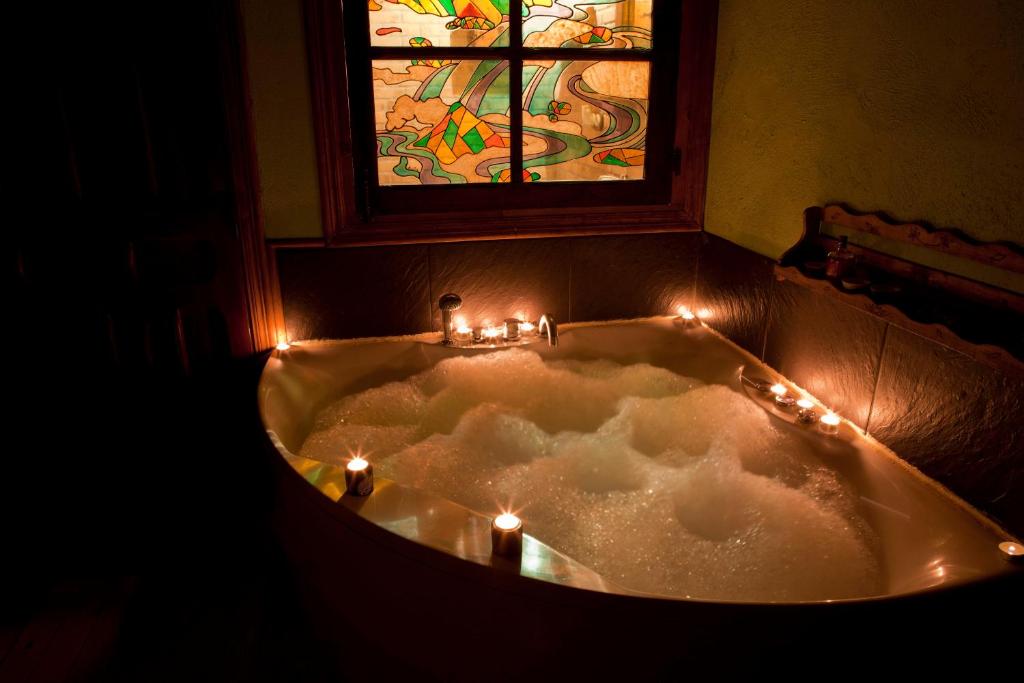 a bath tub with candles and a stained glass window at La Casa del Kender in Casas del Abad