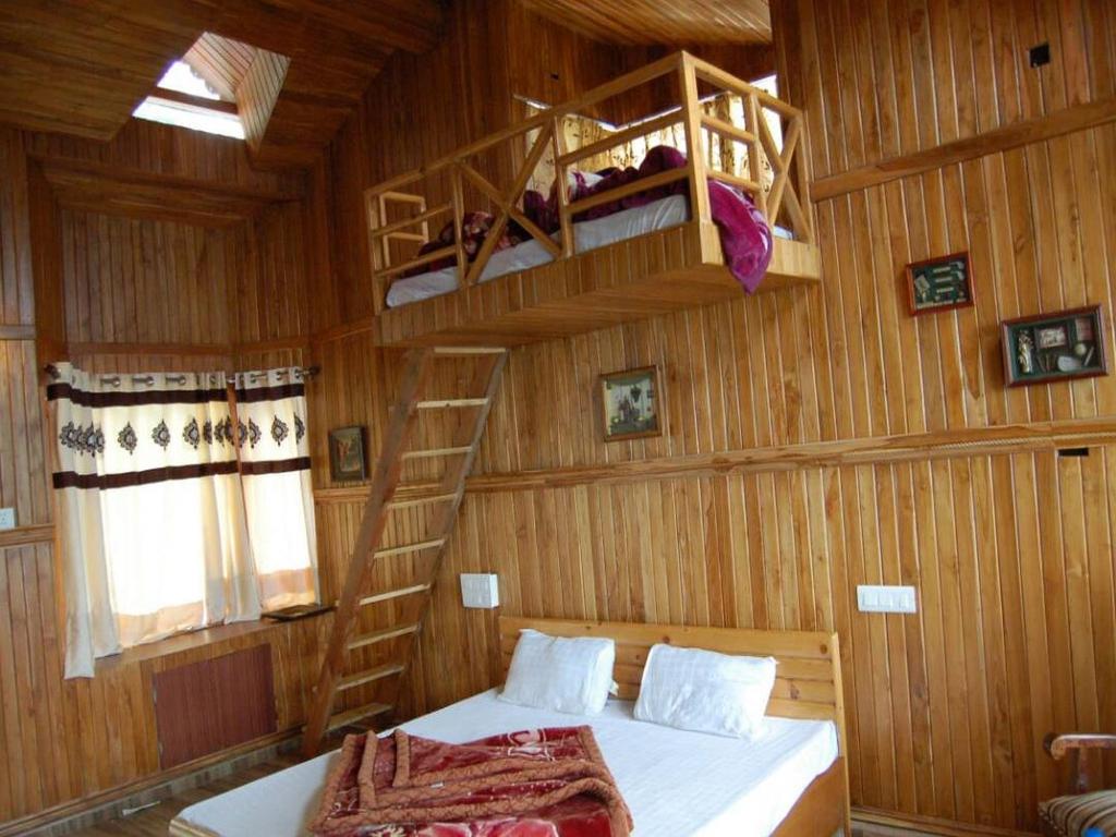 a bedroom with two bunk beds and a ladder at Royal Dutch Resorts and Doll Museum in Mukteswar