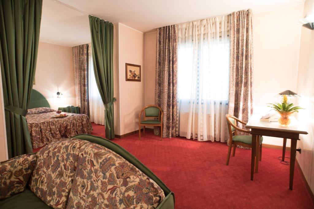 a hotel room with a bed and a desk and a window at Hotel Tessarin in Taglio di Po