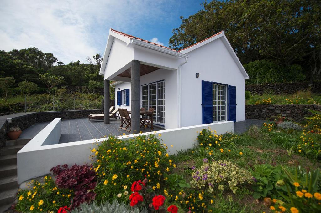 a small white house with a patio and flowers at Casa do Chafariz (Casas do Capelo) in Varadouro