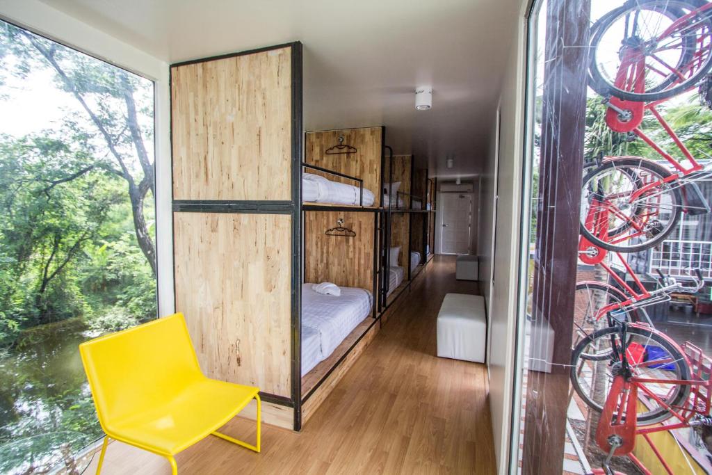 1 dormitorio con litera y silla amarilla en Ducati Bike Box Hotel en Buriram
