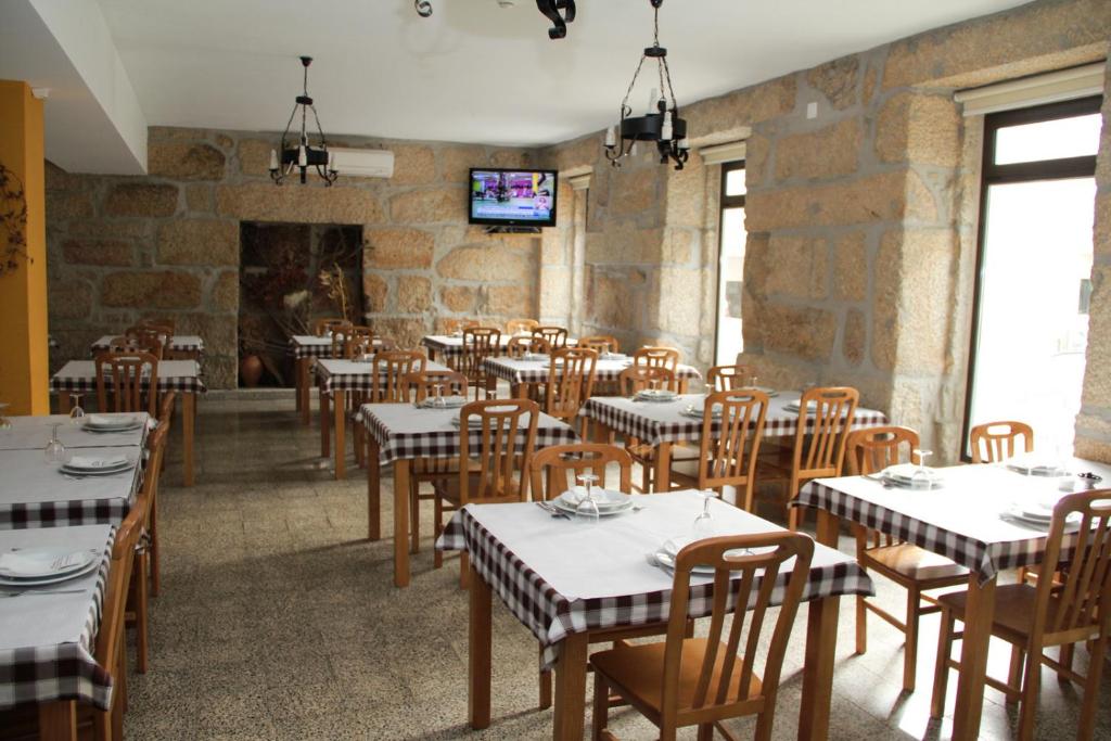 une salle à manger avec des tables, des chaises et une télévision dans l'établissement Residencial Parque, à Celorico da Beira