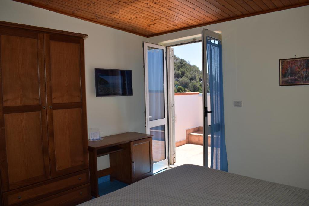 een slaapkamer met een bed en een deur naar een balkon bij Hotel La Certosa in Massa Lubrense