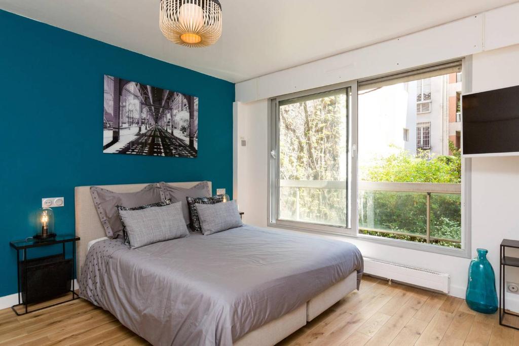 Schlafzimmer mit einem Bett mit blauer Wand in der Unterkunft Appartement d'architect neuf proche Tour Eiffel P78 in Paris