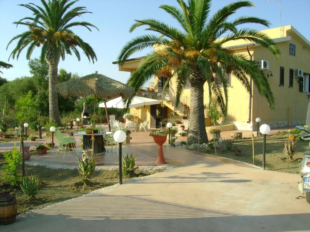 einen Innenhof mit Palmen und ein Gebäude in der Unterkunft Villa dei giardini in San Leone