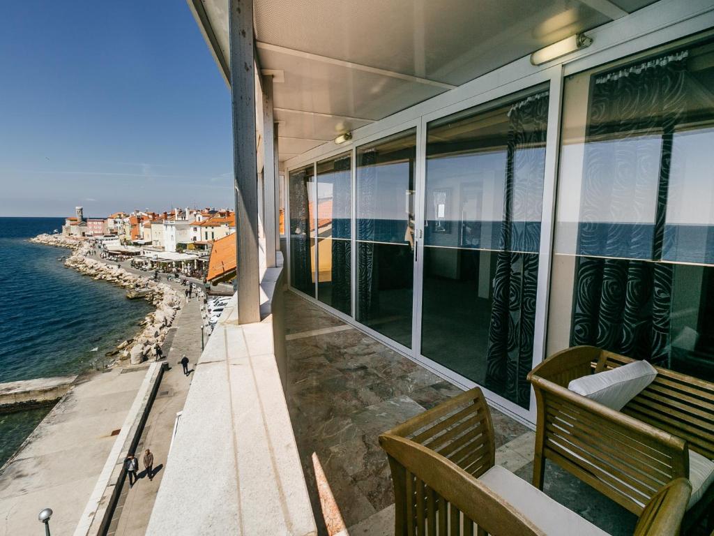 a balcony of a building with two benches and the ocean at Hotel Piran in Piran