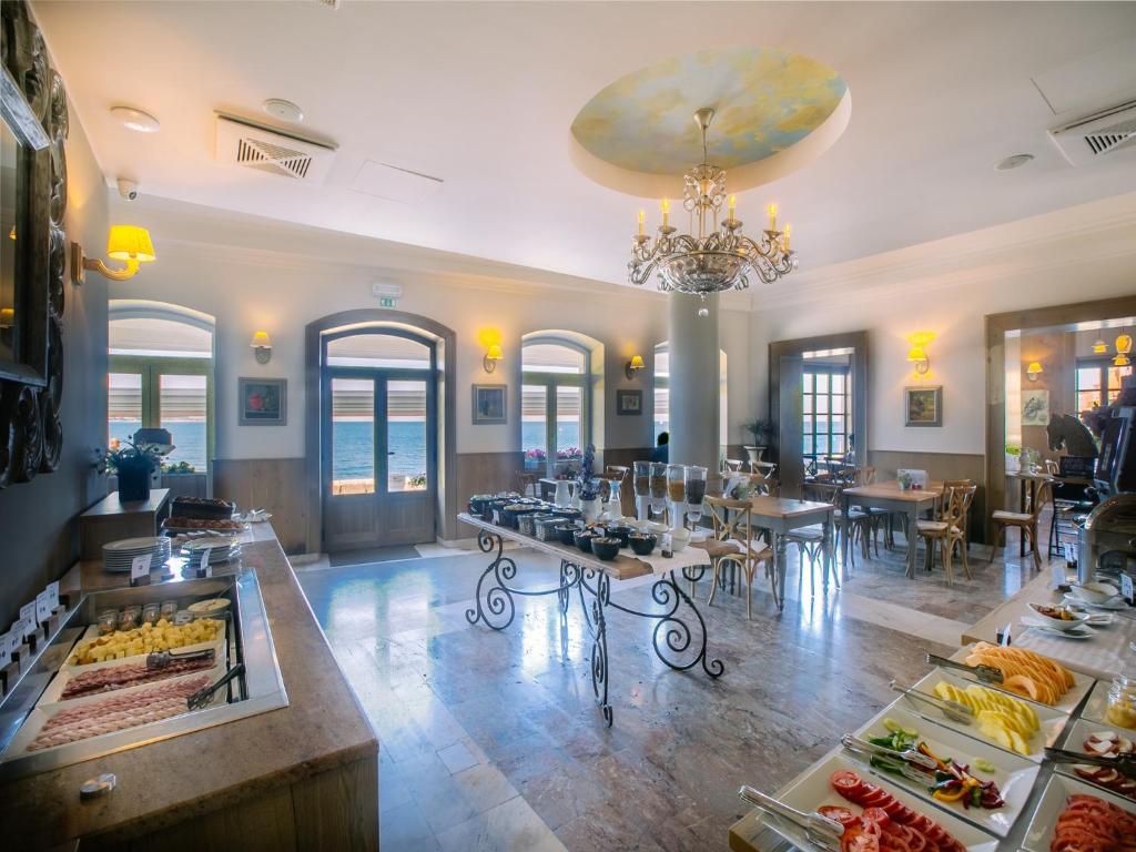 a restaurant with tables and chairs and a chandelier at Hotel Piran in Piran