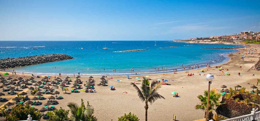 a beach with umbrellas and people in the water at Apartamento Las Veronicas in Arona