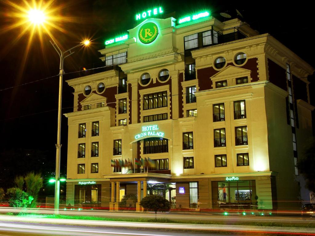 un bâtiment avec une horloge en haut de celui-ci la nuit dans l'établissement Cron Palace kosher Tbilisi Hotel, à Tbilissi