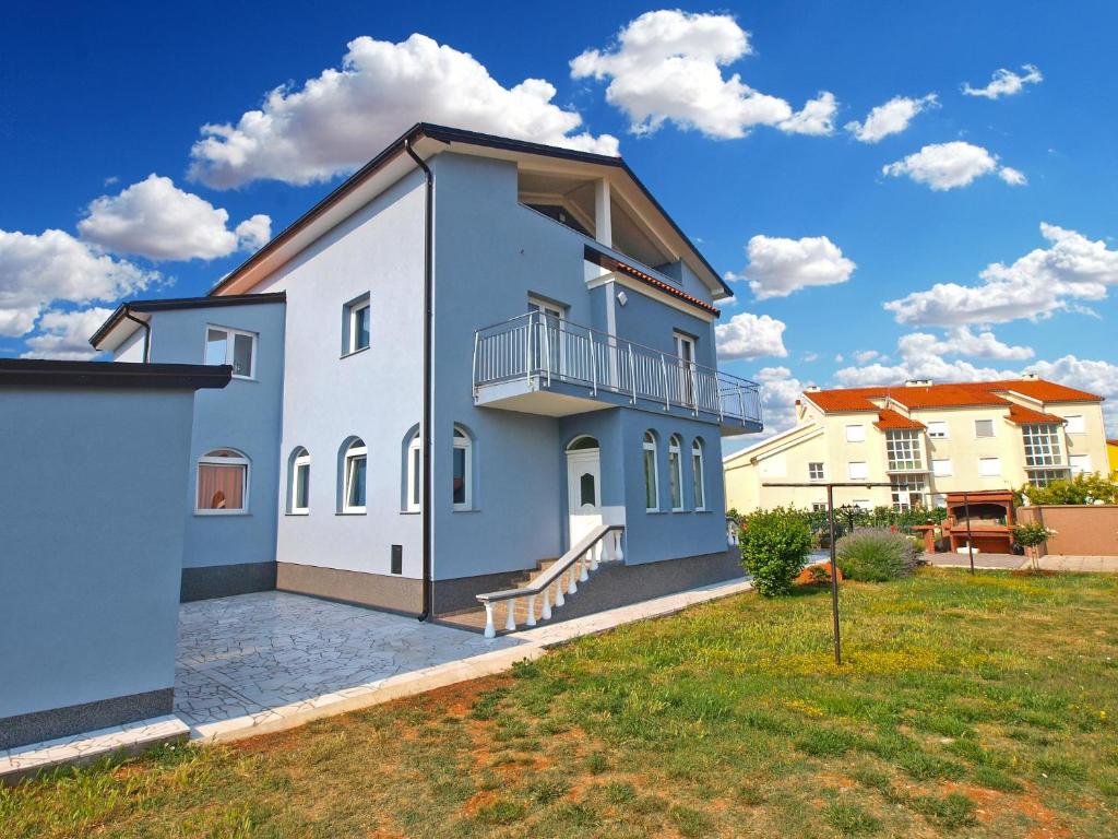 a blue and white house with a yard at Apartments Dragica 1251 in Fažana