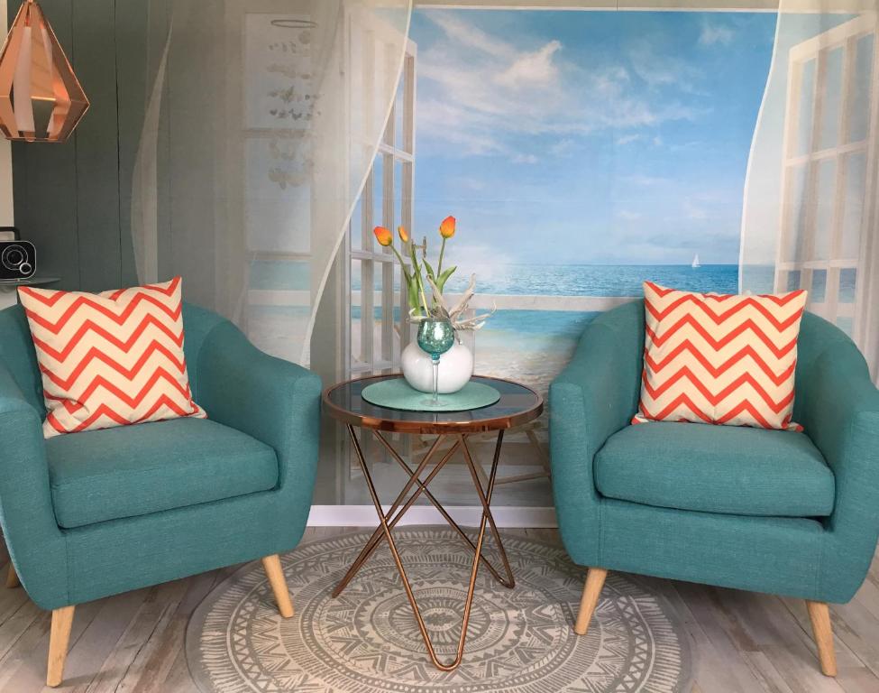 two chairs and a table in a room with a painting at Wohlfühl-Apartments in Zingst in Zingst