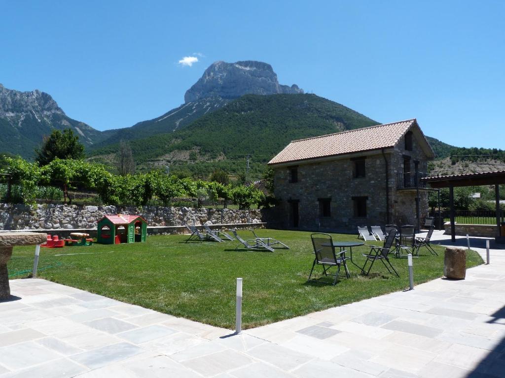 a yard with chairs and a building with a mountain at Puerta de Ordesa Garden in Laspuña