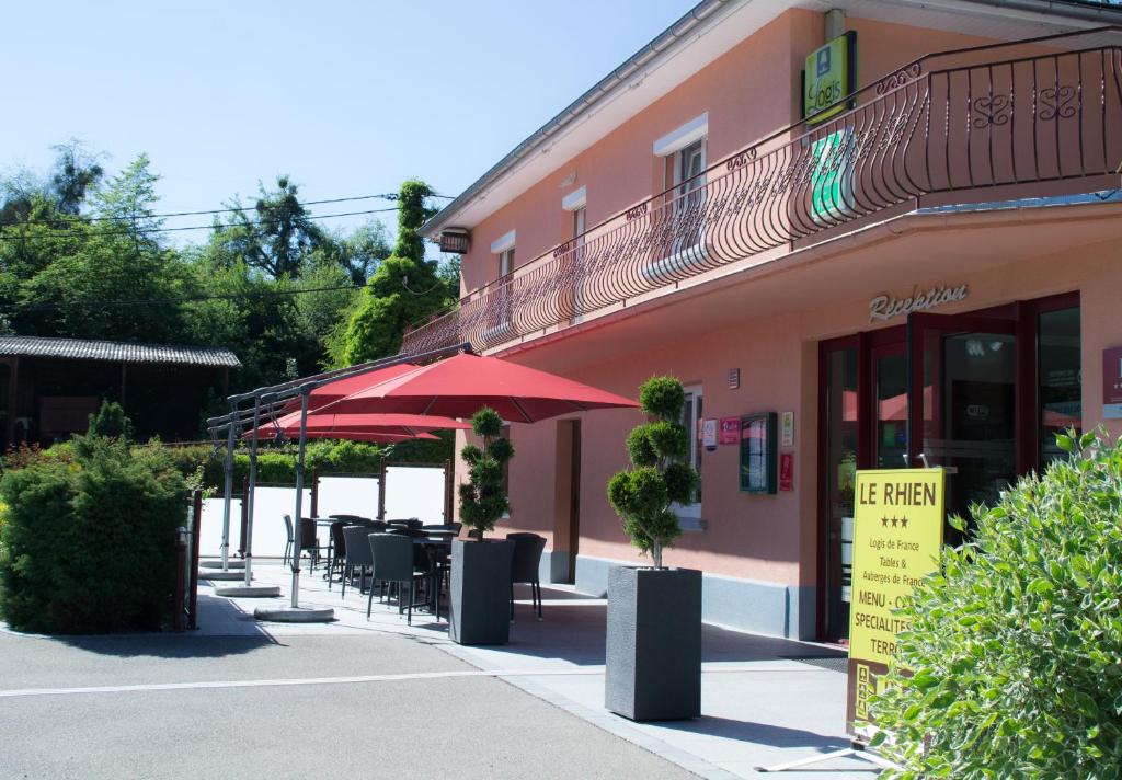 un restaurant avec des tables, des chaises et un parasol rouge dans l'établissement Le Rhien Hôtel-Restaurant, à Ronchamp