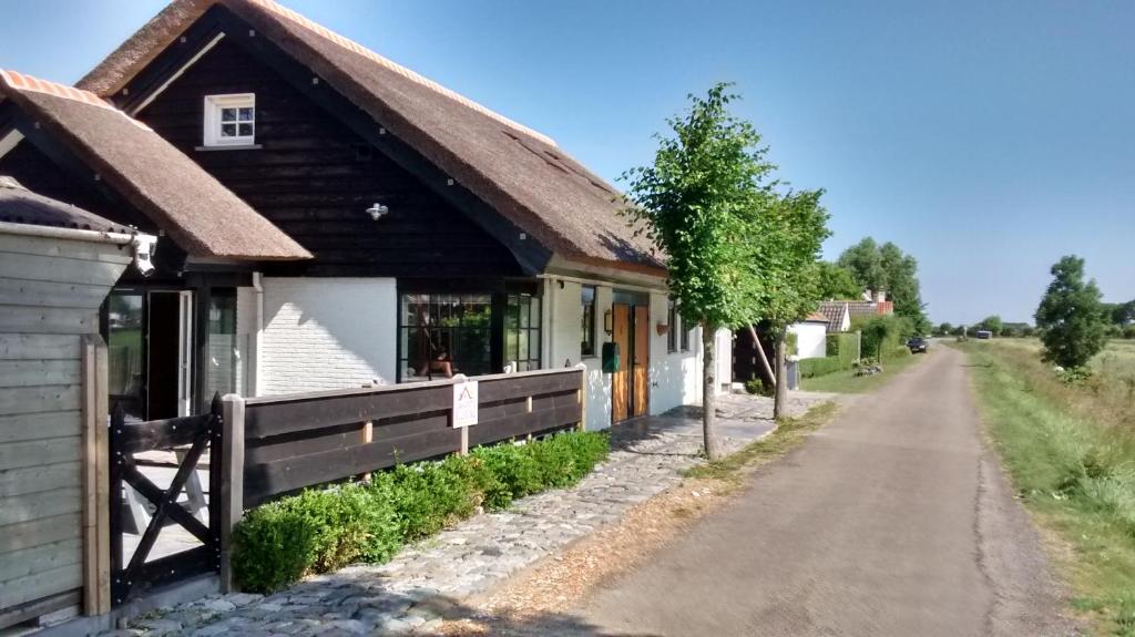 un antiguo edificio con una valla al lado de una carretera en Luxe kamer Cadzand, en Cadzand