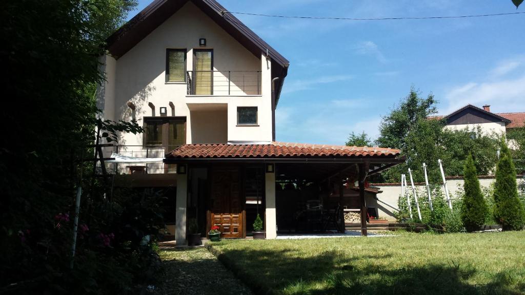 a white house with a balcony and a yard at Nature Villa Sarajevo in Rakovica