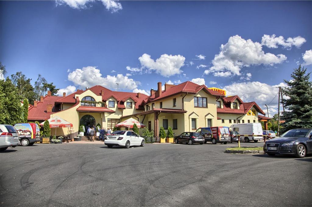 a large house with cars parked in a parking lot at Zajazd Podjadek in Osjaków