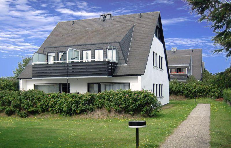una gran casa blanca con techo negro en Aalhues-Ferienwohnung-ueber-2-Etagen-fuer-4-Erwachsene-und-1-Kind en Westerland