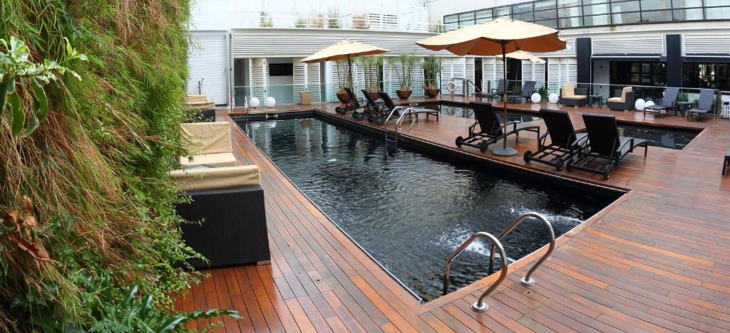 a swimming pool with tables and chairs on a deck at Novotel Buenos Aires in Buenos Aires