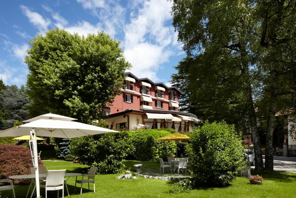 a hotel with tables and umbrellas in front of a building at Albergo Milano Snc in Lanzo dʼIntelvi