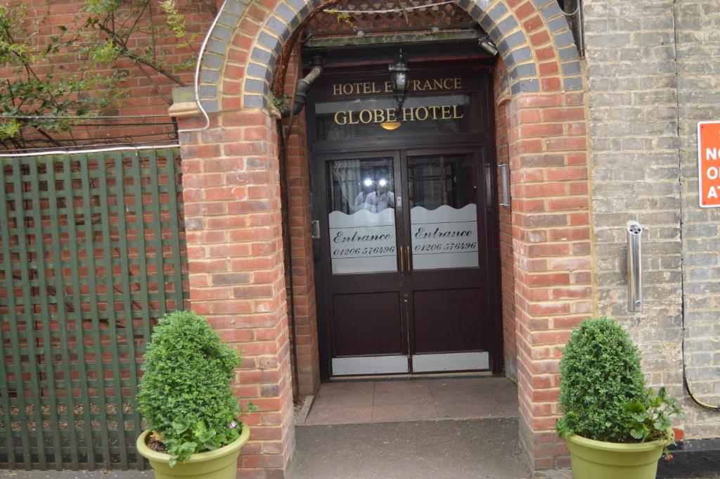 a door to a clove house with two plants in front at Globe Hotel in Colchester