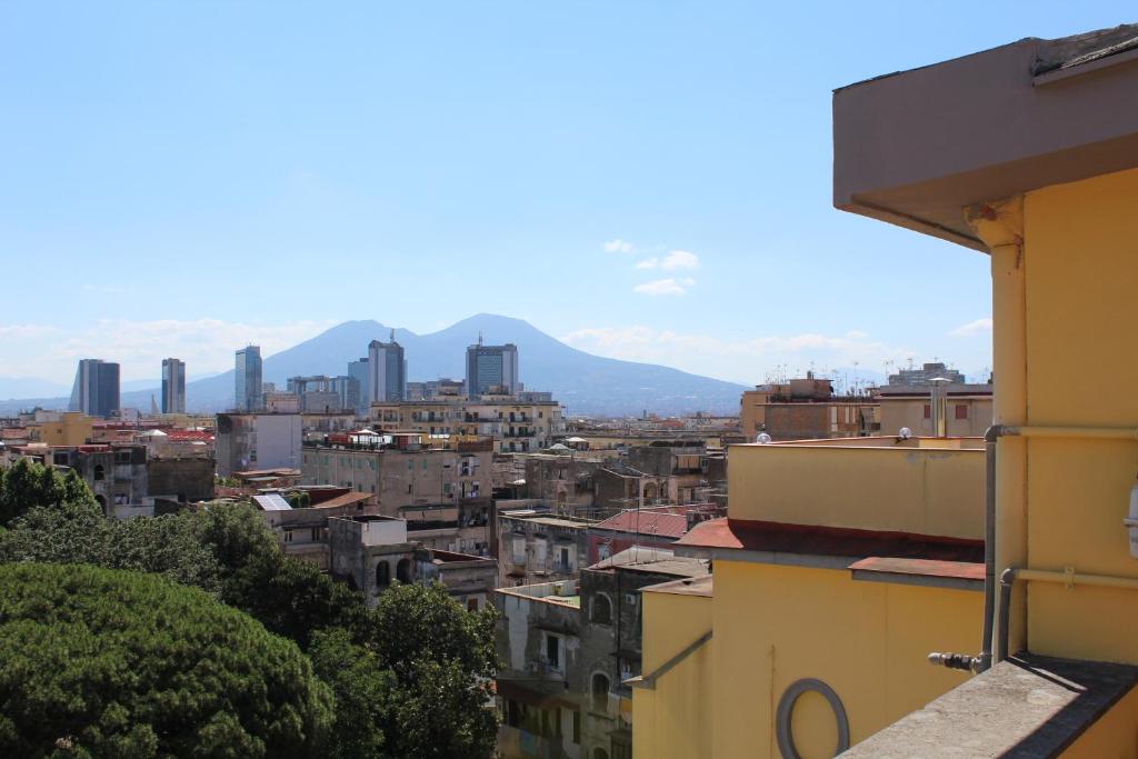 vista su una città con edifici e montagne di L'occhio sul Vesuvio appartamento con terrazza privata e casa vacanza senza terrazza privata a Napoli