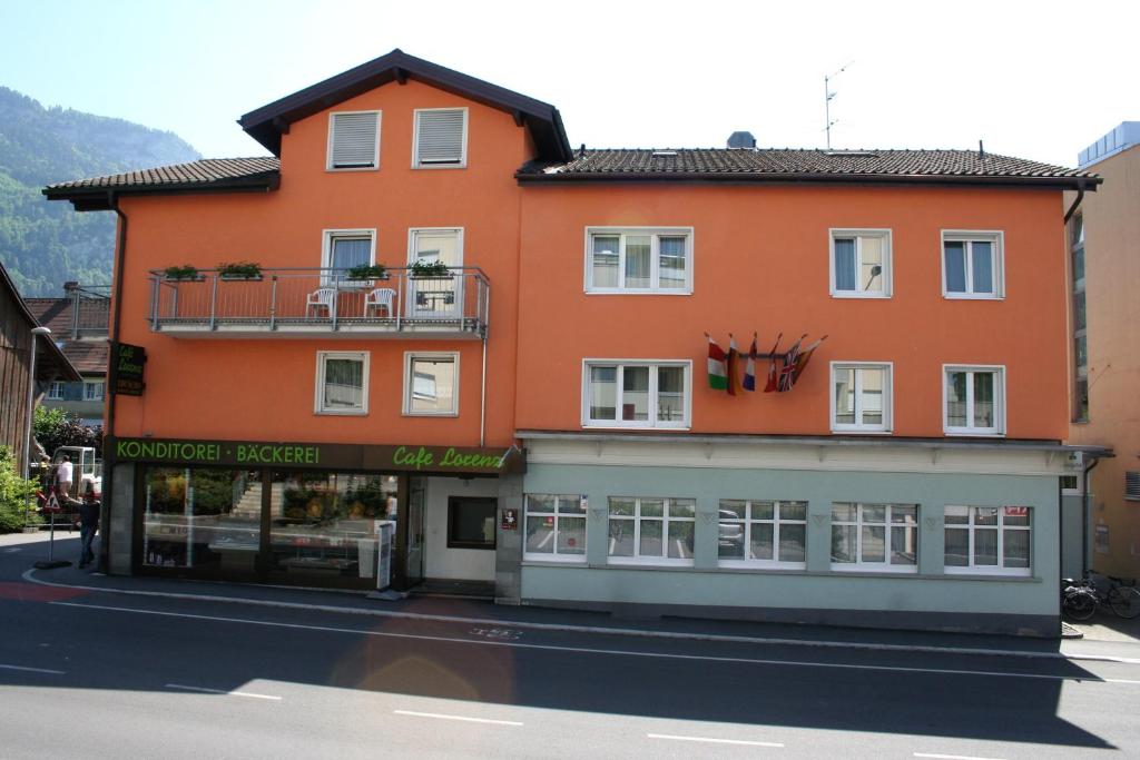 ein orangefarbenes Gebäude auf einer Straße mit einem Geschäft in der Unterkunft Hotel Cafe Lorenz in Hohenems