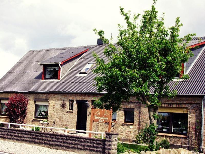 a brick house with a black roof and a tree at Apartment-1 in Schönhagen