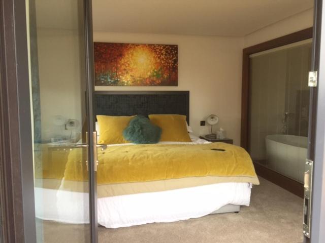 a bedroom with a yellow bed and a bath tub at Antrim House Guest Rooms & Suites in Portrush