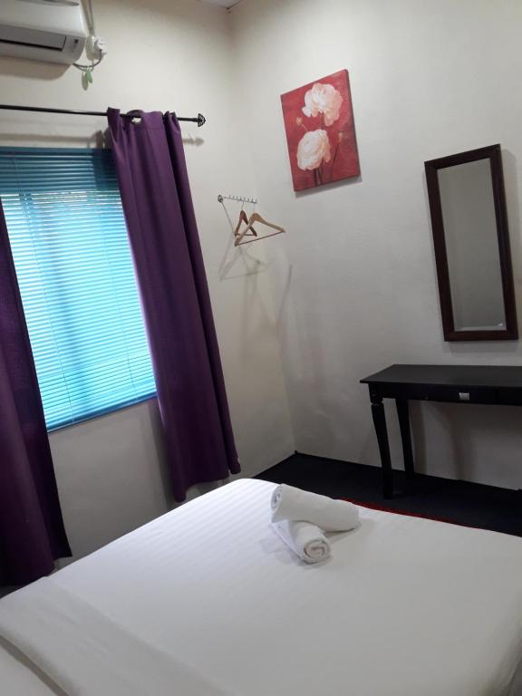 a bedroom with a bed and a desk and a window at Alsafffa Homestay in Pantai Cenang