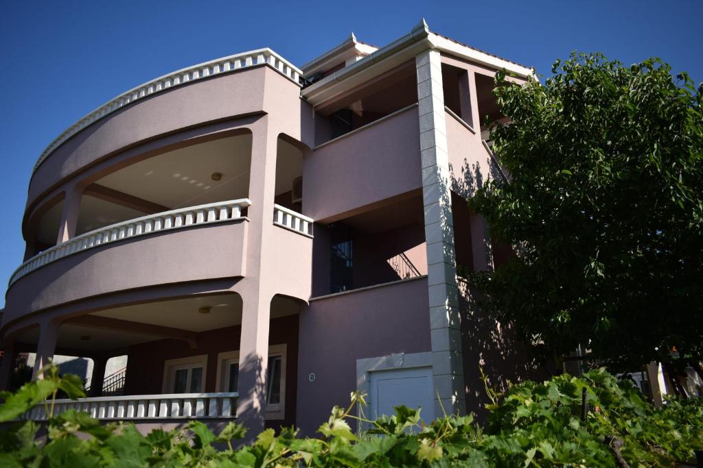 a large building with a tree in front of it at Apartments Bazina in Kaštela
