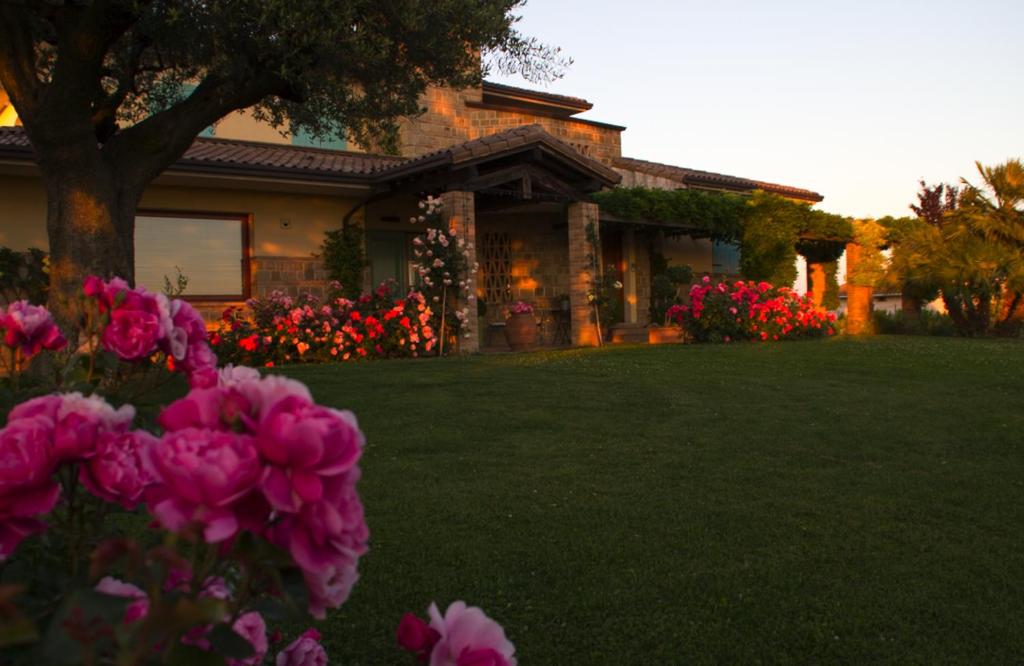 a house with pink flowers in front of a yard at Il Giardino delle Rose in Santa Maria Nuova