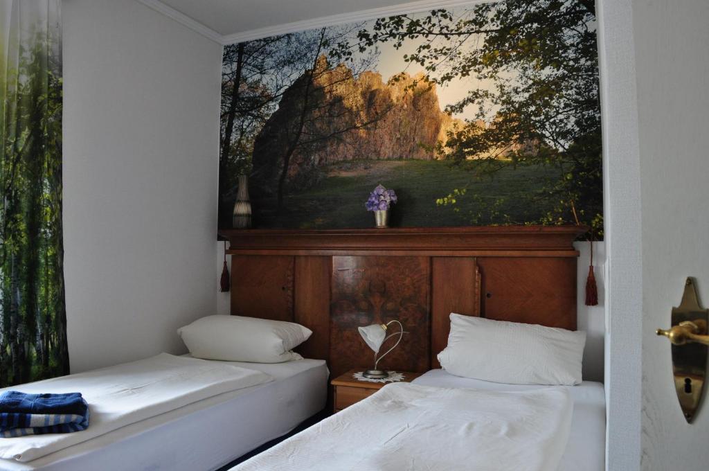 two beds in a room with a painting on the wall at Landgasthof Eschbacher Katz in Usingen