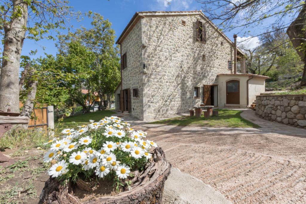 a stone house with flowers in front of it at B&B Podere Legnotorto in Castel del Piano