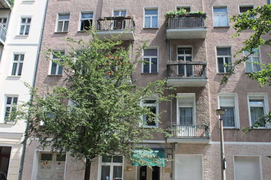 un edificio de apartamentos con un árbol delante de él en Hotel Novalis en Berlín
