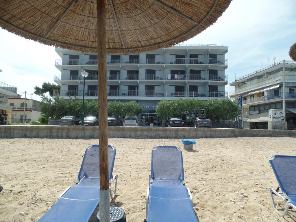 duas cadeiras de praia e um guarda-sol na praia em Plage Hotel em Nea Peramos