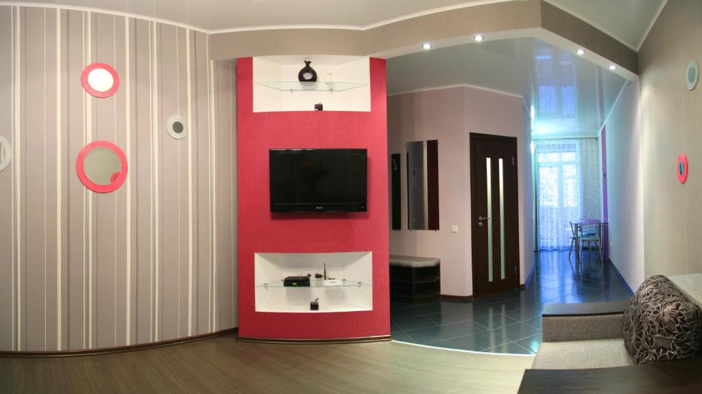 un soggiorno con parete rossa e TV di Apartment Dekabrystiv a Mykolaïv