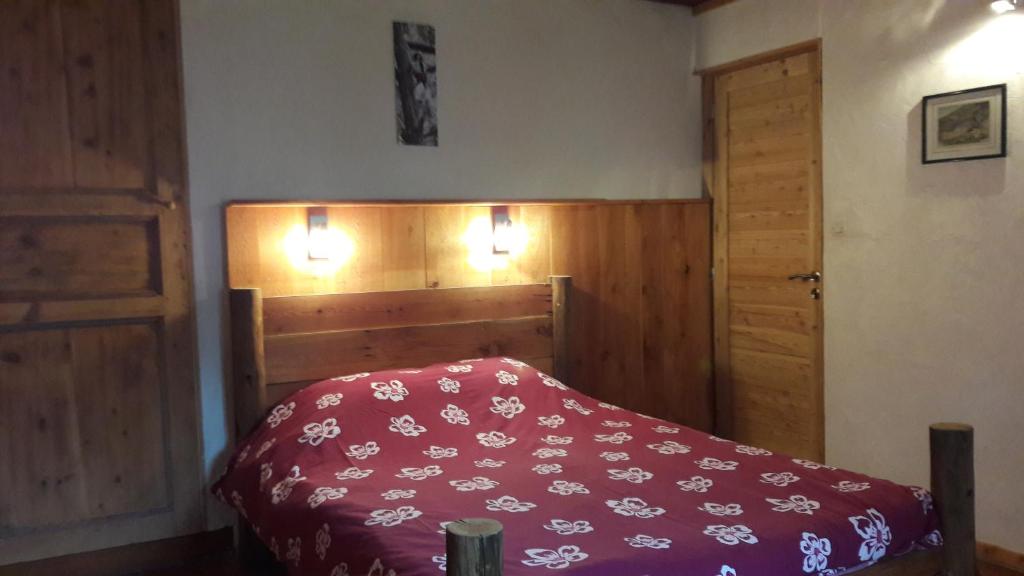 a bedroom with a bed with a red comforter at Le Berger Gourmand in Saint-Véran