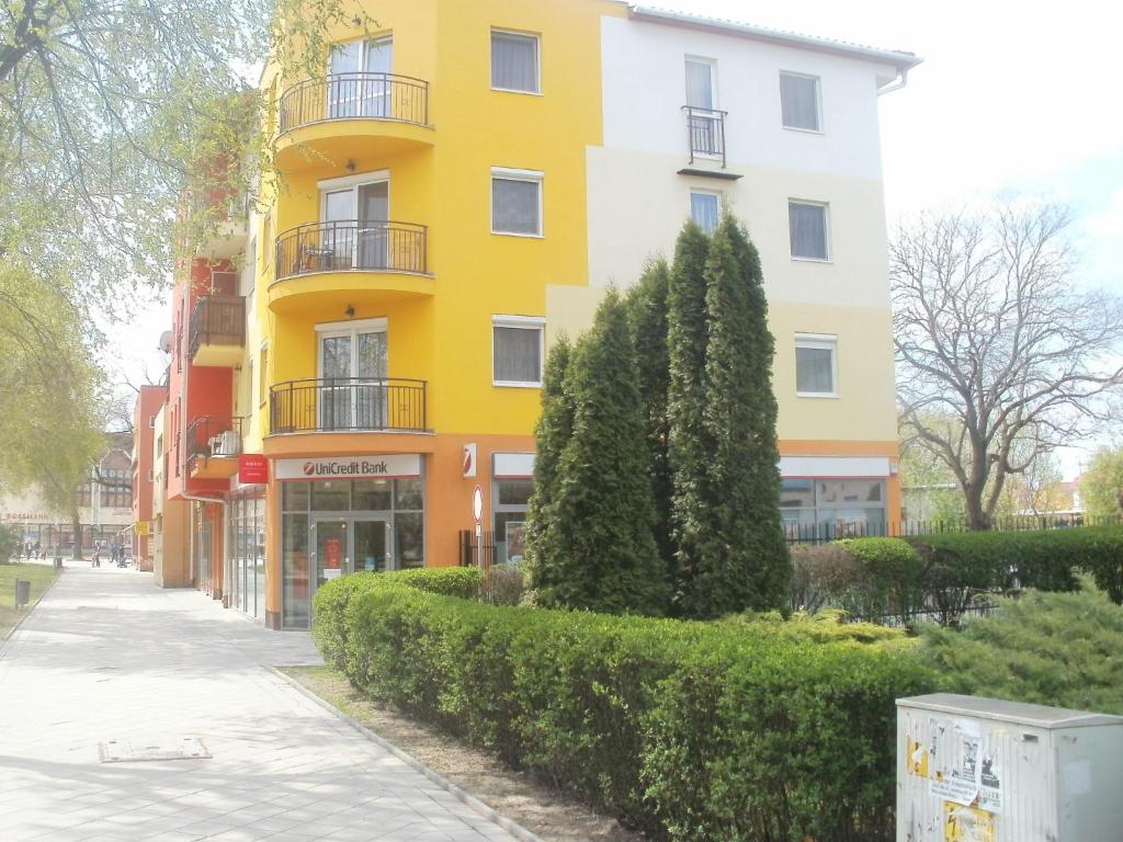 un edificio amarillo al lado de una calle en Apartman Ottó en Hajdúszoboszló