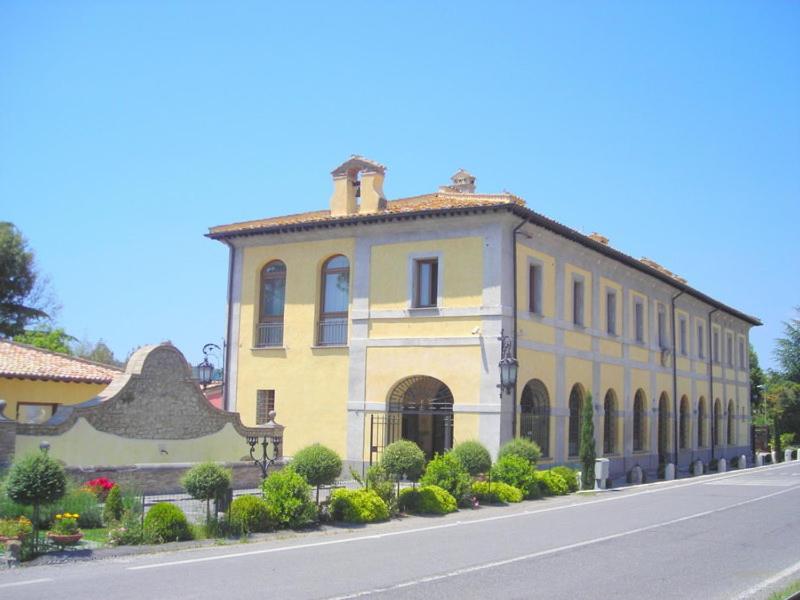 um grande edifício amarelo no lado de uma estrada em Relais Il Postiglione - Antica Posta dei Chigi em Campagnano di Roma