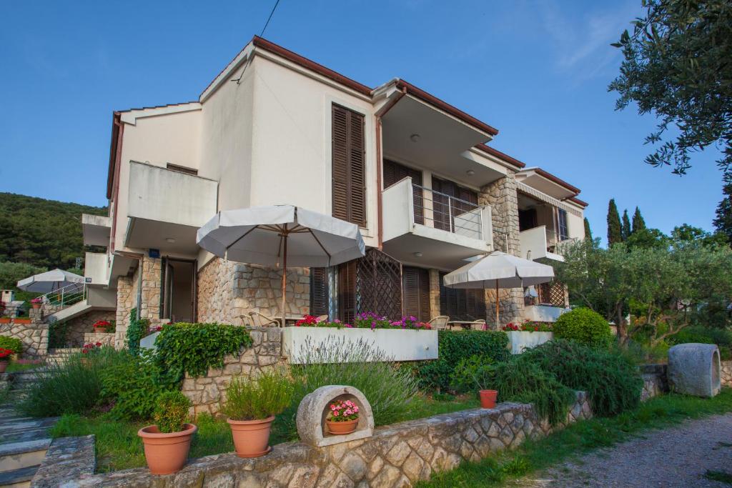 a house with umbrellas in front of it at Apartments Ljubo & Lili in Cres