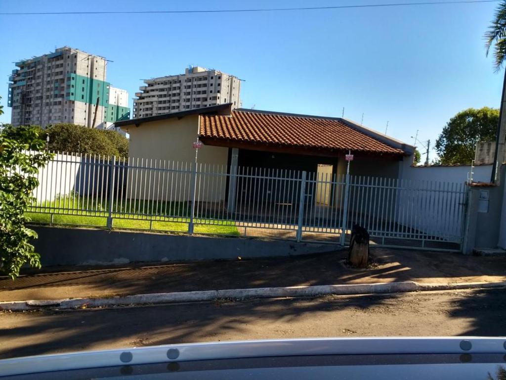 a cat sitting next to a fence in front of a house at Casa beira thermas in Olímpia