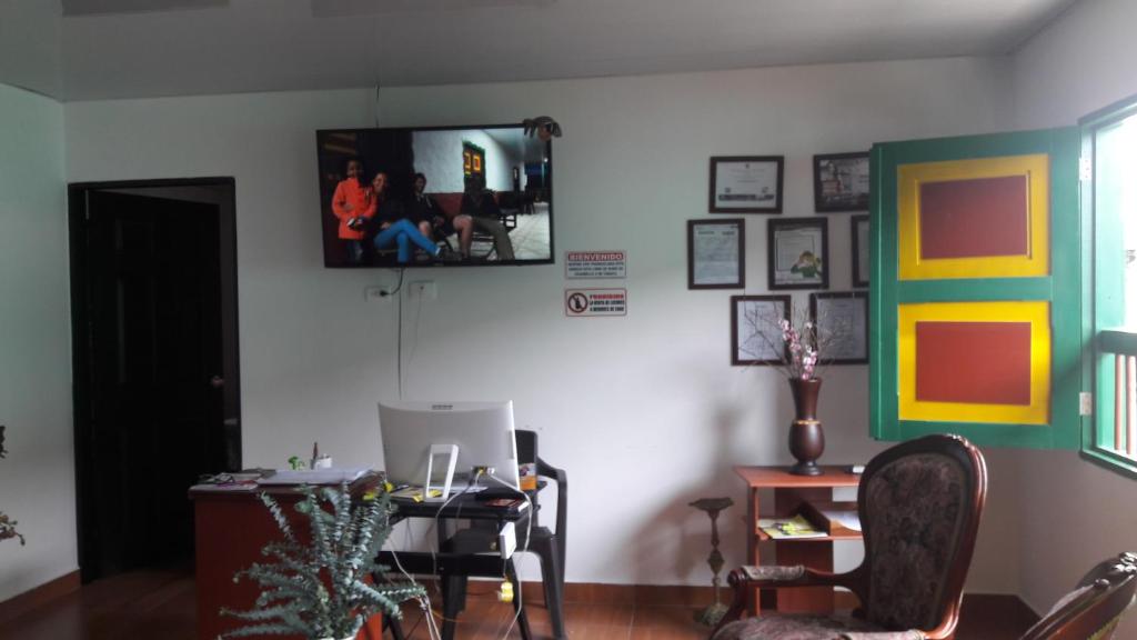 a living room with a desk and a tv on the wall at Hostal Casa de Los Taitas in Salento