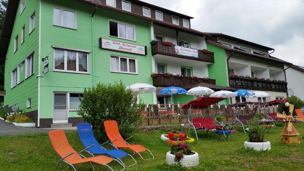 ein Gebäude mit Stühlen und Sonnenschirmen davor in der Unterkunft Hotel-Pension Dressel in Warmensteinach