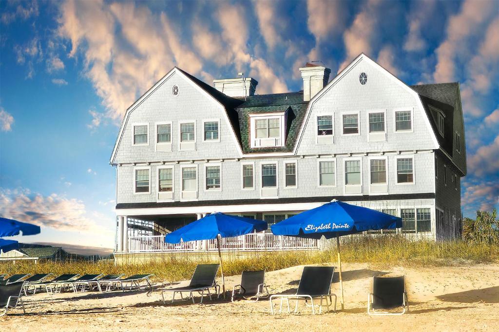 uma grande casa branca com cadeiras e guarda-sóis na praia em Elizabeth Pointe Lodge em Fernandina Beach