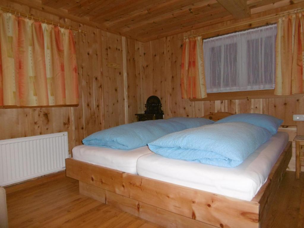 a bed with blue pillows in a wooden room at Ferienhaus Anderles-Alm in Heiligenblut