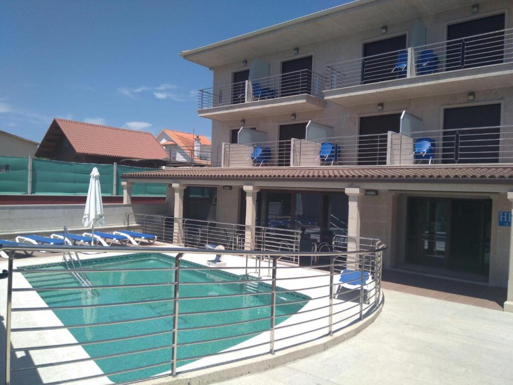 a swimming pool in front of a building at Hotel A Bota in Portonovo