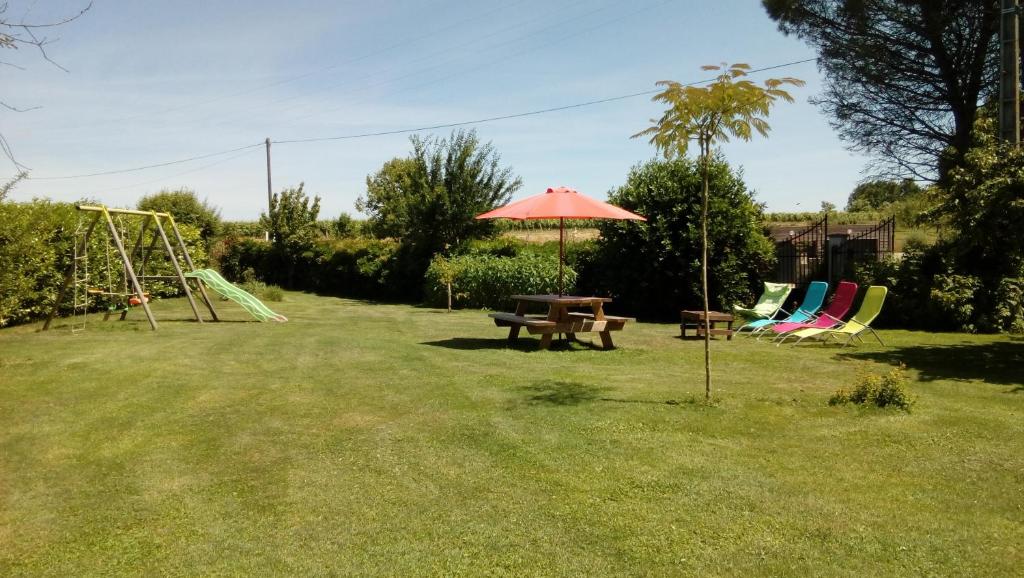 a park with a picnic table and chairs and an umbrella at Gîte 5 personnes au calme avec jardin, piscine, proche d'Amboise in Mosnes