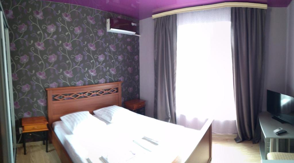 1 dormitorio con 1 cama y papel pintado con motivos florales en On Sevastopolskoy en Gelendzhik