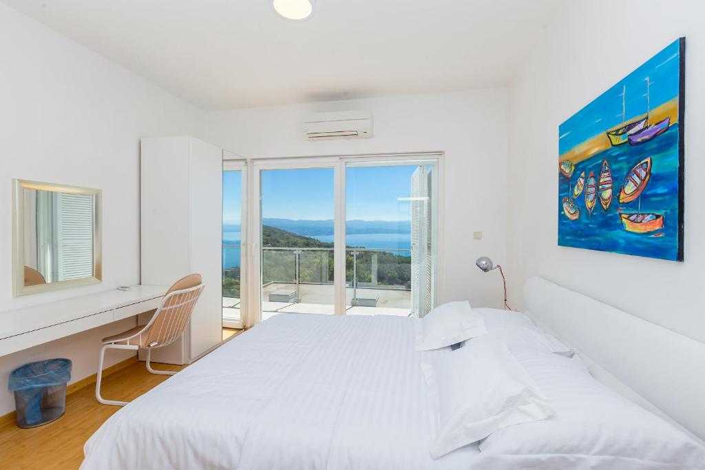 a white bedroom with a bed and a desk and a window at Villa Sveti Petar - with heated pool and outdoor jacuzzi in Opatija